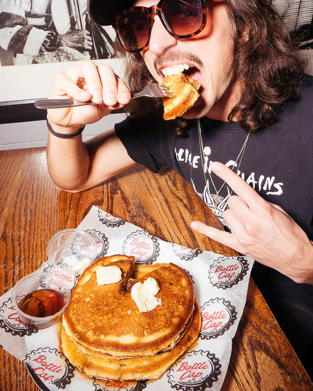 A man holding up the rock sign with his hand and eating pancakes at Bottle Cap in Nashville